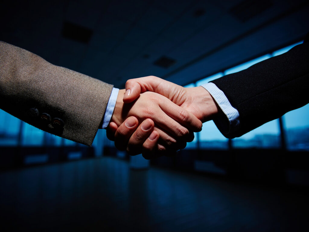 Executivos firmando parceria estratégica para expansão de negócios no setor de seguros corporativos, simbolizando colaboração e crescimento.
